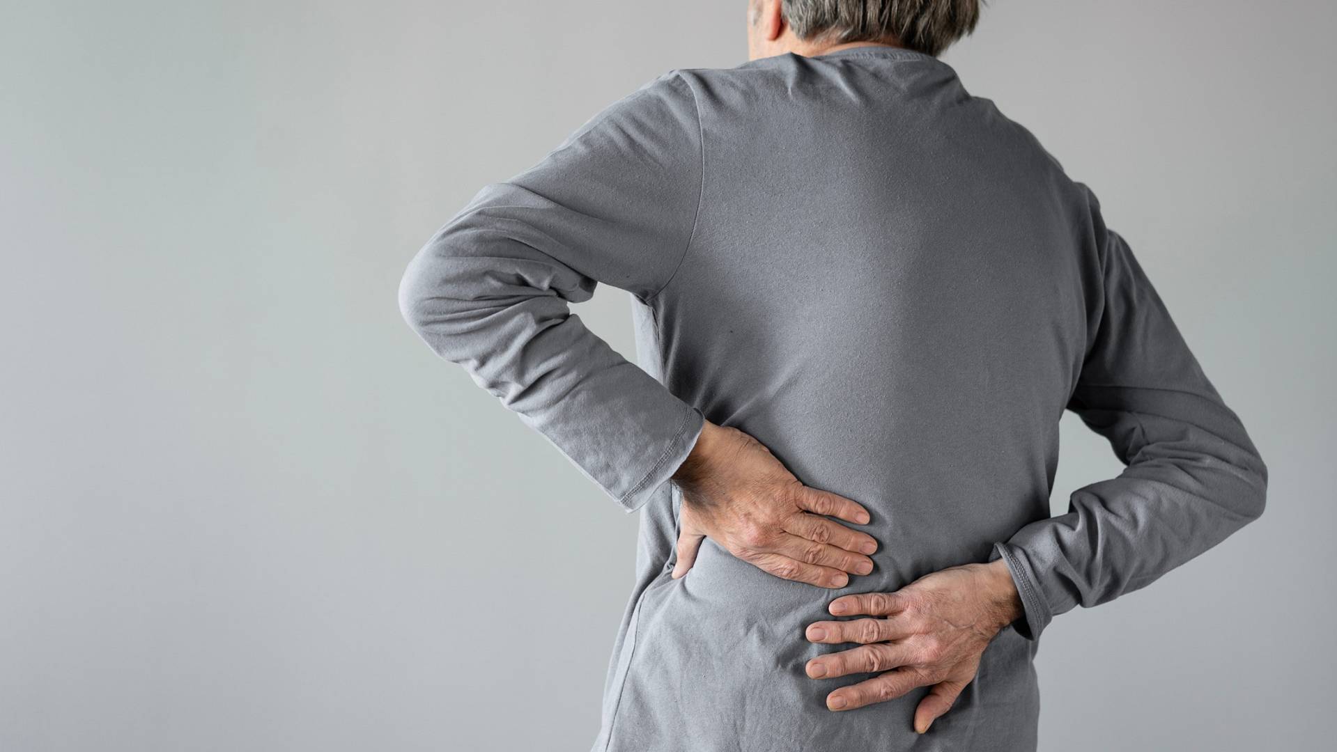 Zdjęcie pacjenta trzymającego bok silny ból w okolicy lędźwiowej podczas ataku kolki nerkowej i napadu kolki nerkowej (atak kamicy nerkowej)